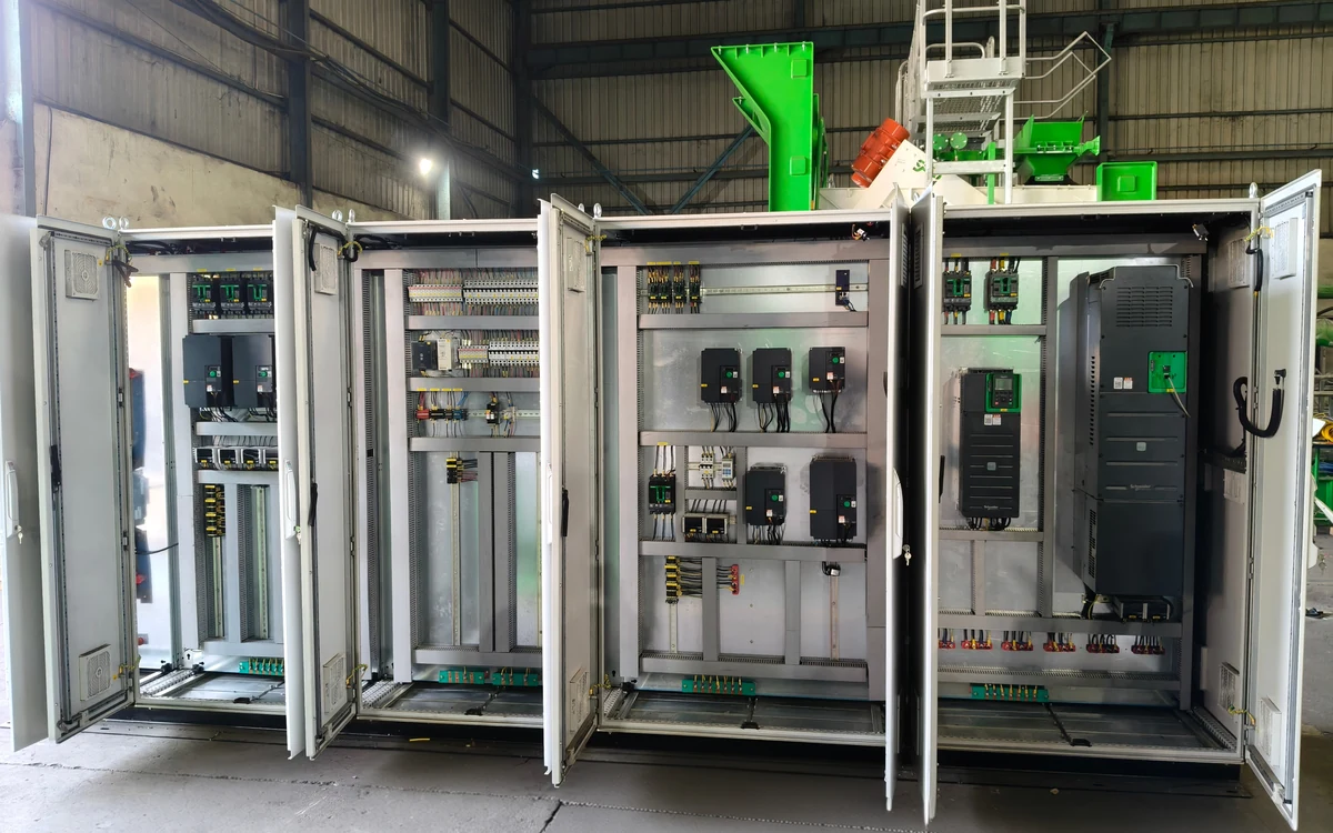 A run of CFlo PLC control panels in the works with every door open, showing the drives, breakers, terminal rails and numbered wiring inside each cubicle, with a plant module behind them