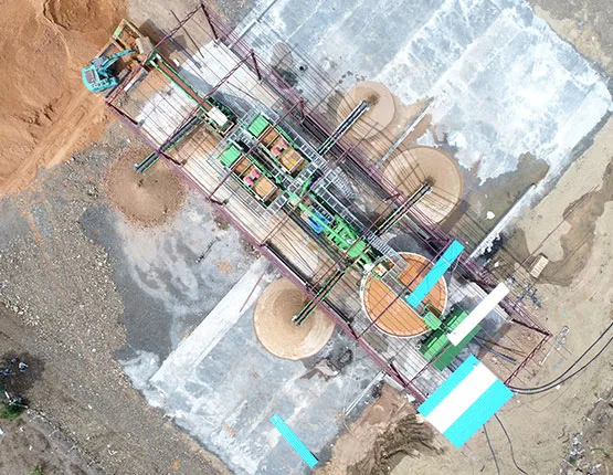 Aerial view of a processing plant beside white-lined settling ponds on red ground