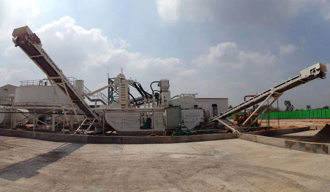 A washing plant with a circular thickener and raised conveyors on a concrete pad
