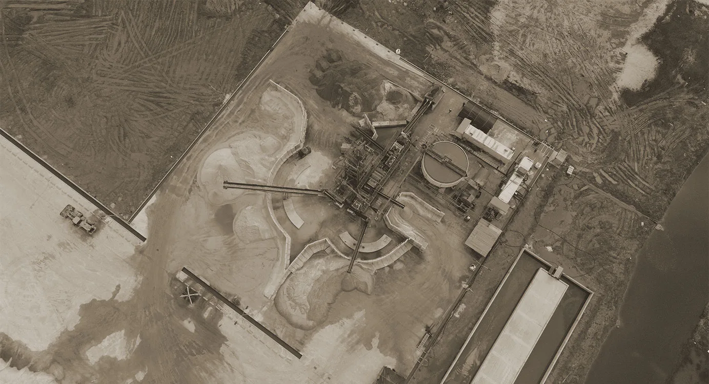 Aerial view of a plant with settling ponds and stockpile bays laid out on cleared ground