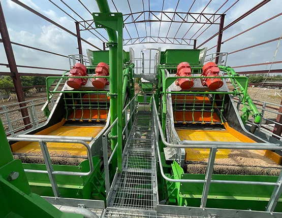 Twin green dewatering units seen from above, with red drive motors and lined feed boxes