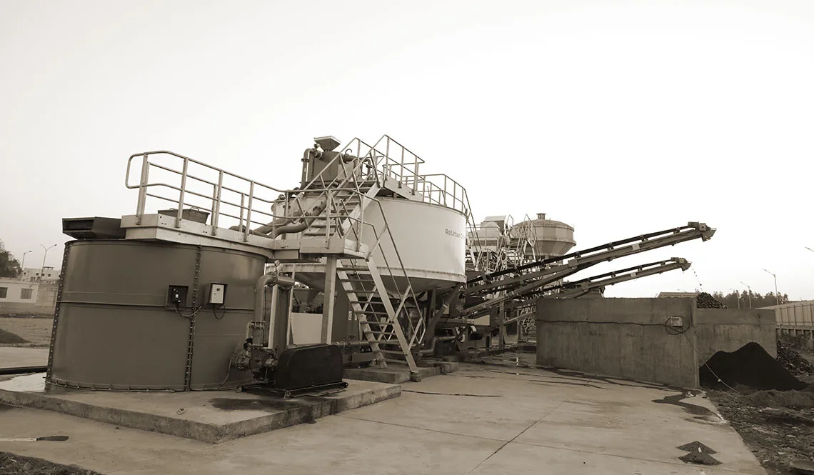 A compact plant with a circular tank, walkways and feed conveyor on a hard standing