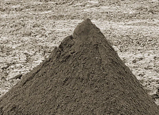A conical stockpile of fine grey product on a bed of coarser stone
