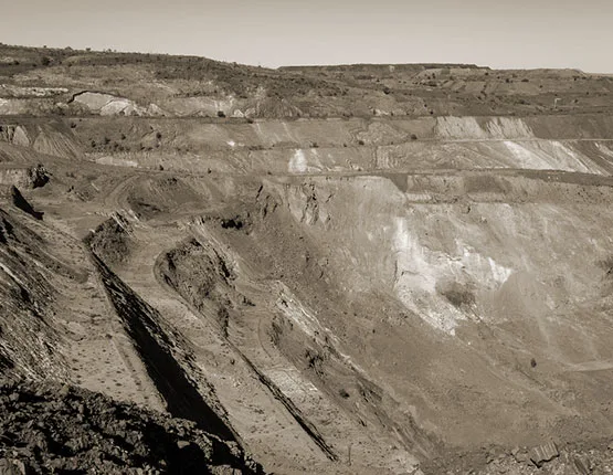 Benched terraces of an open-cast mine with dark overburden in the foreground