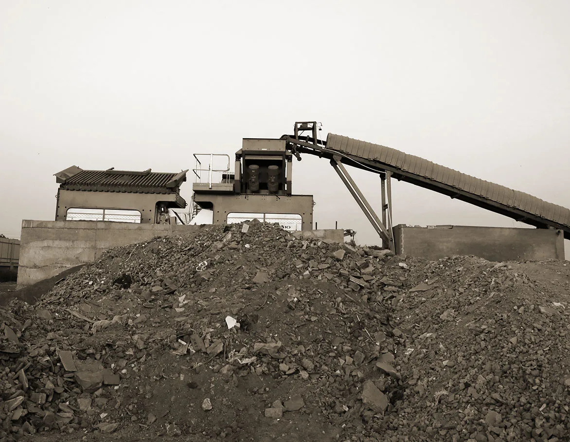 A conveyor discharging a heap of mixed construction and demolition rubble