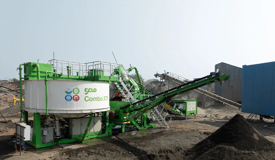 A green CFlo Combo X70 beside a dark stockpile, feed conveyor raised