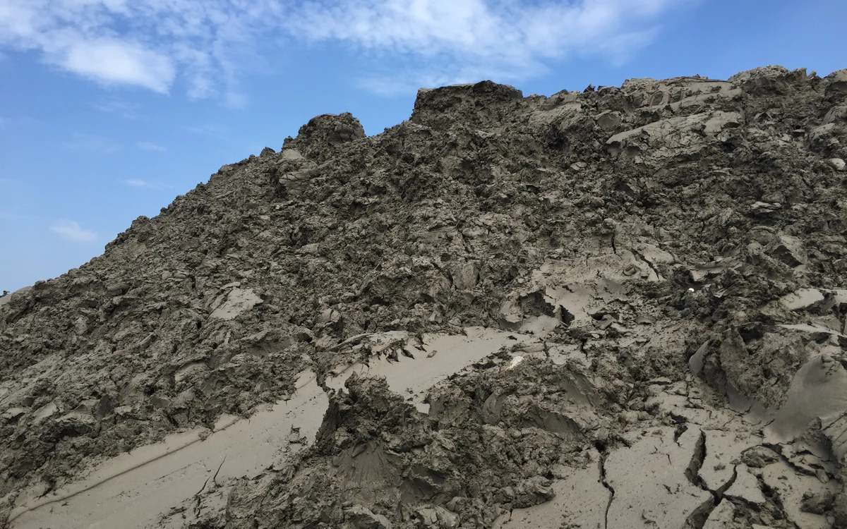 A mountain of Easysettle cake against a blue sky, the surface dried and cracked into firm blocks solid enough to walk and drive on