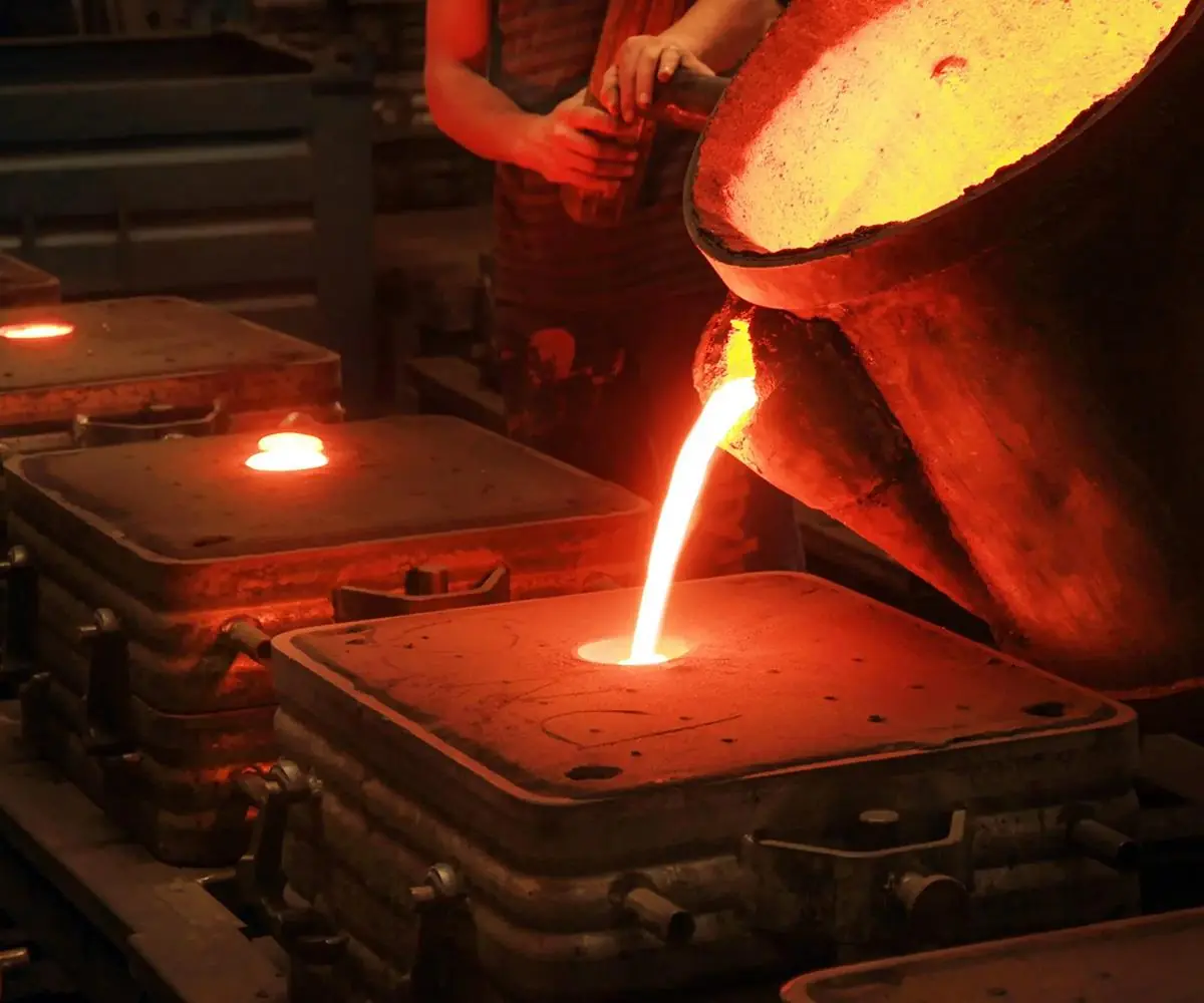 Molten metal pouring from a foundry ladle into a casting mould