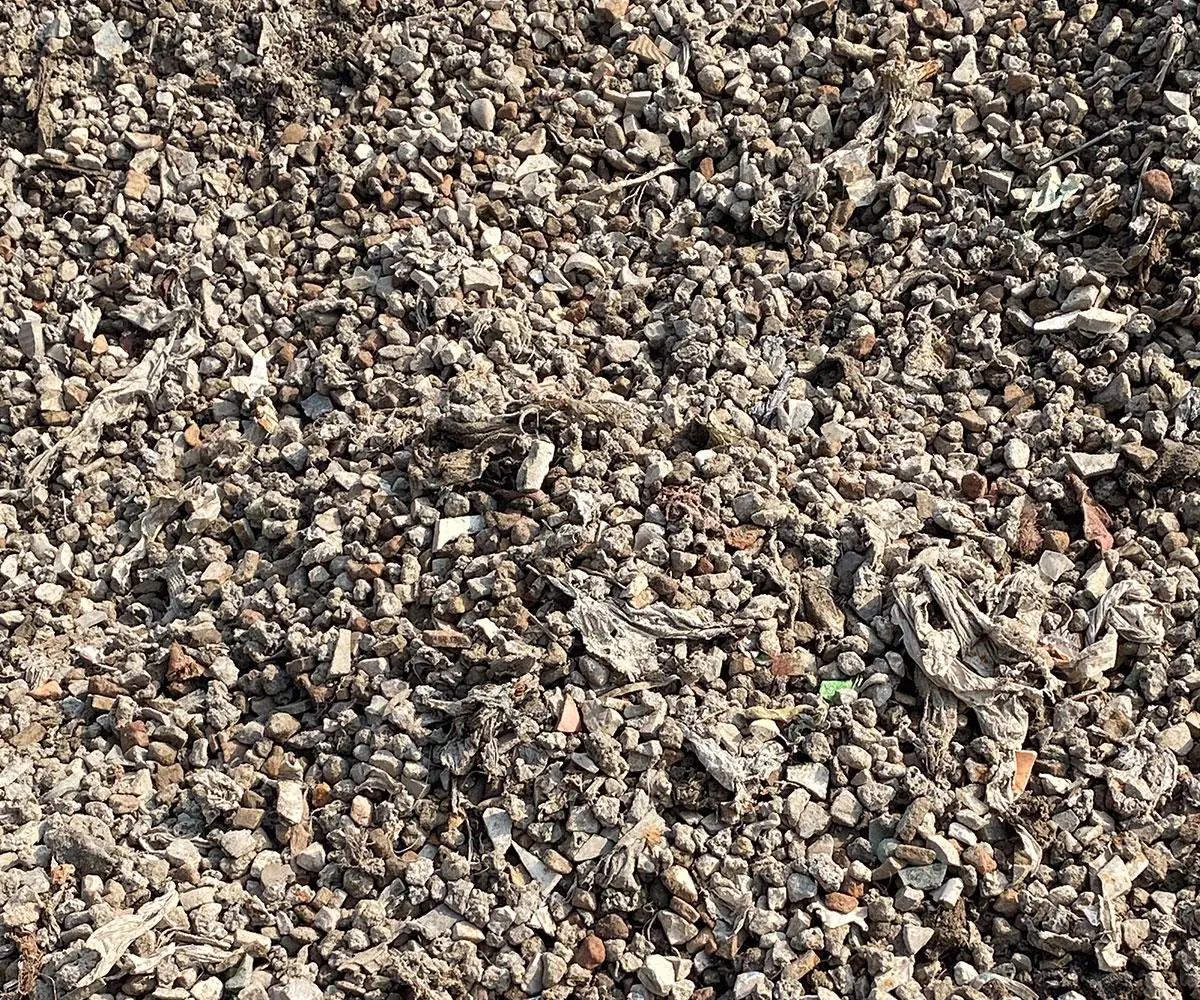 Close-up of incinerated bottom ash: mixed grey fragments, wire and glass