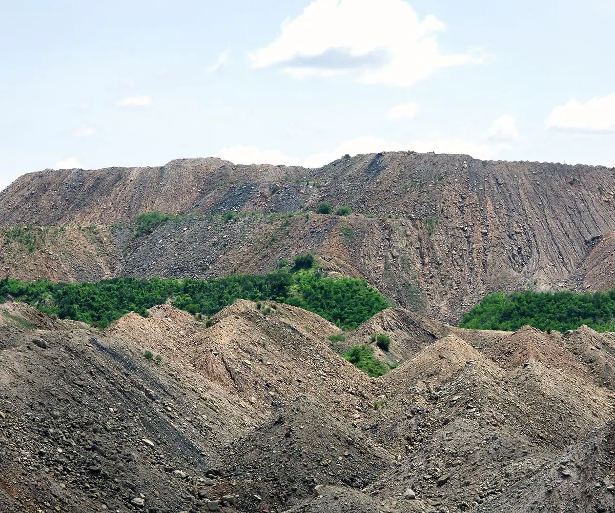 Stripped mining overburden forming steep grey ridges with vegetation returning