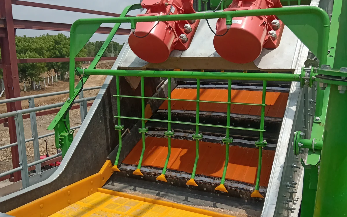 Screenmax FS86 High Precision Fines Screen working on site, twin red exciter motors above a stepped deck of orange polyurethane panels, green spray bars repulping the bed at each step and a yellow dewatering panel at the discharge end