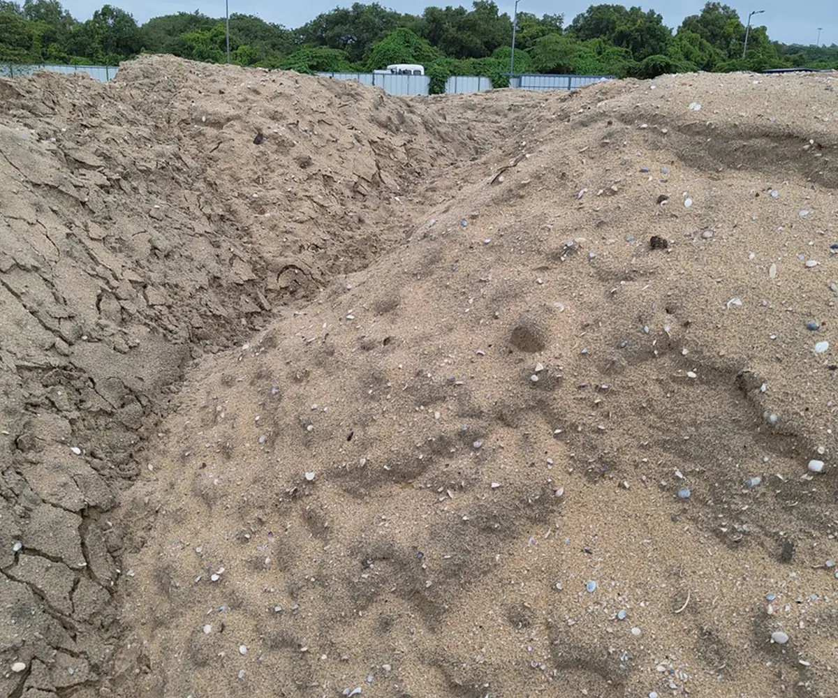 A bank of pale dredged sea sand with a scoured, rippled surface